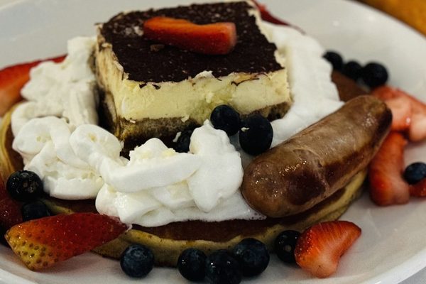 Tiramisu Pancake with whipped cream, strawberries, blueberries and a sausage link