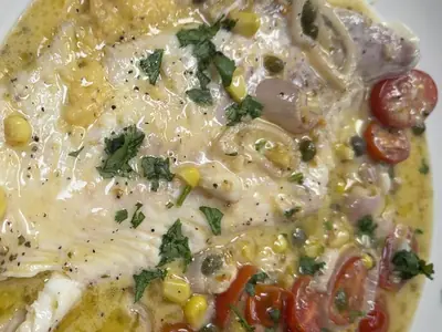 Fish and grits with cherry tomatoes, corn and lemon butter sauce