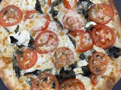 White pizza topped with tomato slices and basil