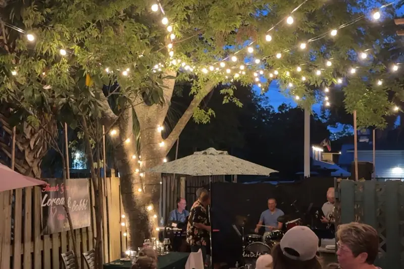Live band playing in the courtyard at night under string lights while guests watch